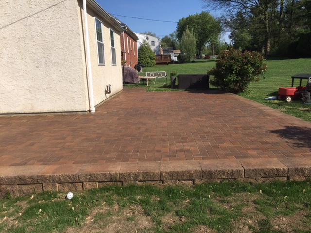 large raised rectangular hardscape patio with brown and red bricks